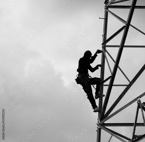 Lineman climbing on transmission line tower in black & white picture