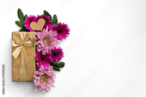 Golden gift box with colorful flowers on white background with copy space on the right