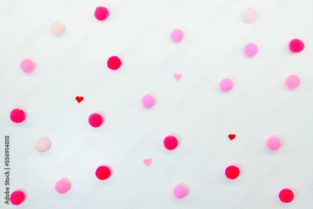 白い柔らかい布を背景に赤やピンクのポンポンと小さなハートを散りばめた水玉模様