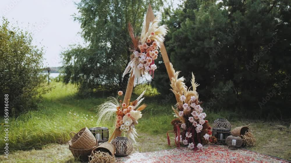 Close-up beautiful boho arch decoration on outdoor wedding ceremony. Floristic flower compositions of pastel colors, dried flowers, wooden chairs and oldfashioned carpet. Summer wedding. Close-up beautiful boho arch decoration on outdoor wedding ceremony. Floristic flower compositions of pastel colors, dried flowers, wooden chairs and oldfashioned carpet. Summer wedding.