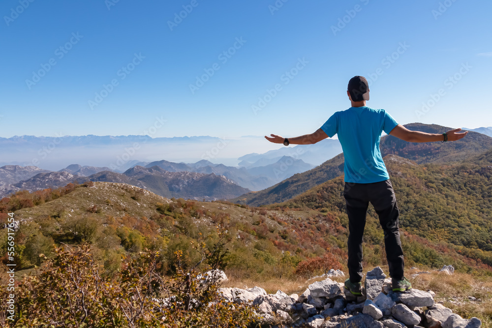 Man on top of Goli Vrh with scenic aerial view on dramatic mountain chains of Dinaric Alps surrounding Lake Skadar National Park, Montenegro, Balkan, Europe. Valley is covered by mystical fog. Freedom