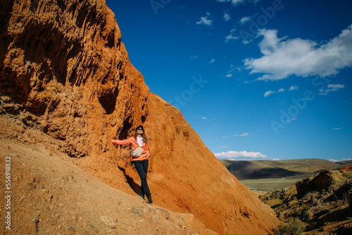 Happy young woman tourist admires red canyon. Brave female hiker in mountains solo trekking. Adventure, wanderlust, sightseeing.