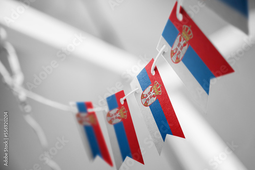 A garland of Serbia national flags on an abstract blurred background