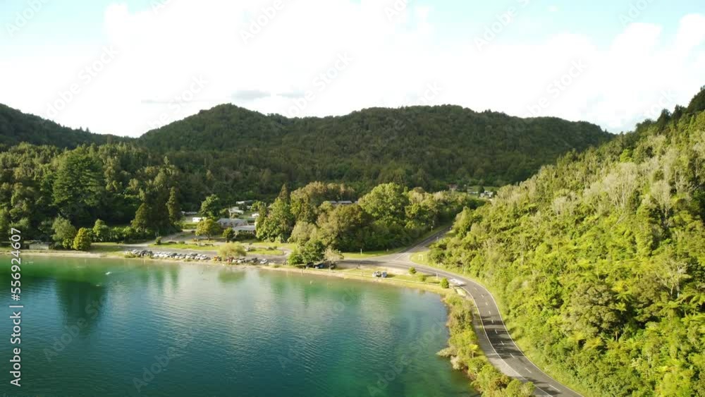 Lakeside holiday campground, blue lake, palm forest road and tourist on paddle bord 4k drone shot in New Zealand Lakeside holiday campground, blue lake, palm forest road and tourist on paddle bord 4k drone shot in New Zealand