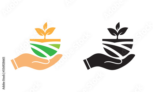 Single hand holding a plant and agriculture land.