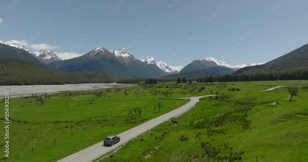 Car travels through New Zealand countryside surrounded by snowy mountains, aerial Car travels through New Zealand countryside surrounded by snowy mountains, aerial