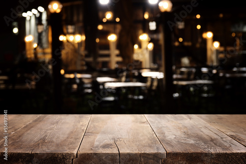 background Image of wooden table in front of abstract blurred restaurant lights