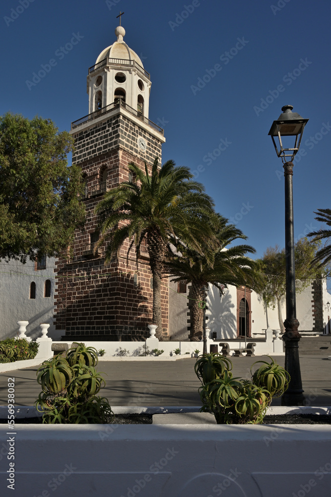 Die Kirche von Teguise auf Lanzarote bei blauem Himmel und mit grünen Palmen