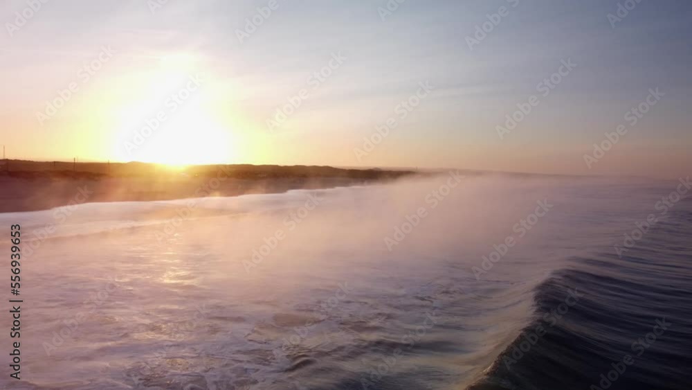 Drone flyover ocean follow wave rolling towards Beach shore shrouded in Mystic fog during sunrise Drone flyover ocean follow wave rolling towards Beach shore shrouded in Mystic fog during sunrise