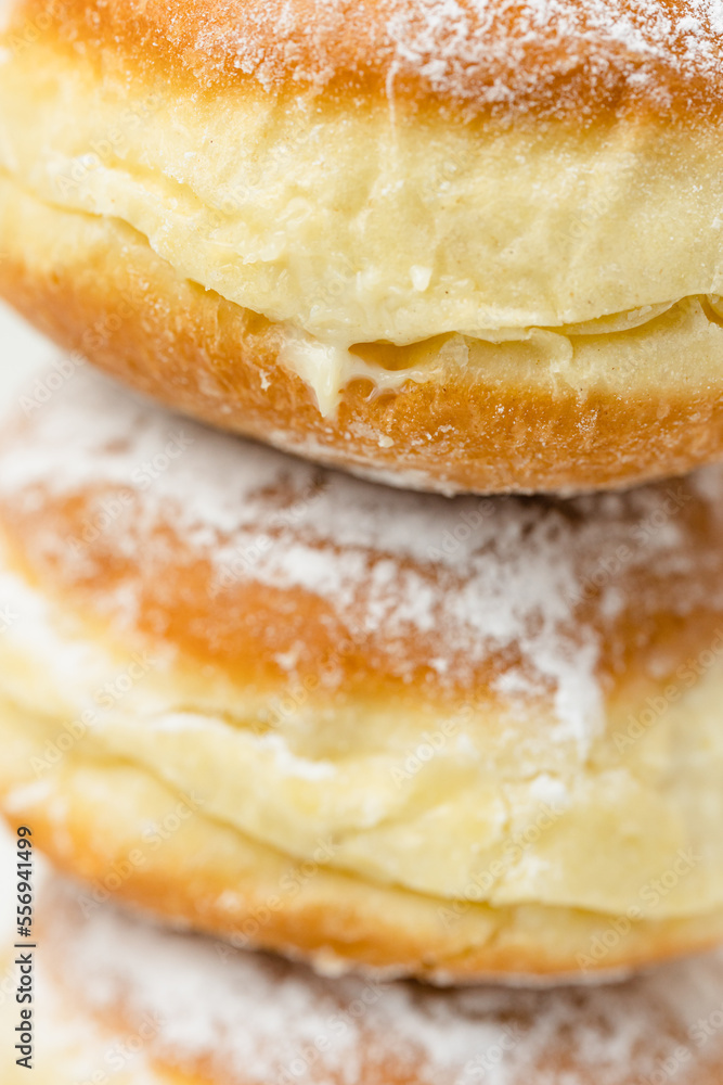 Close up macro shot of stack of Krapfen or Berliner doughnuts dusted with icing sugar, traditional German fried Brioche dough pastry filled with vanilla custard for New Year's party, selective focus Close up macro shot of stack of Krapfen or Berliner doughnuts dusted with icing sugar, traditional German fried Brioche dough pastry filled with vanilla custard for New Year's party, selective focus