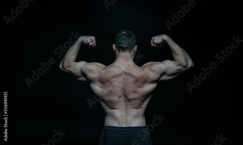 bodybuilder man muscular back in black studio. bodybuilder man muscular back