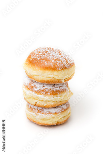 Stack of Krapfen, Kreppel or Berliner doughnuts dusted with powdered sugar on white background, traditional German fried Brioche dough pastry filled with vanilla custard or jam for New Year's party