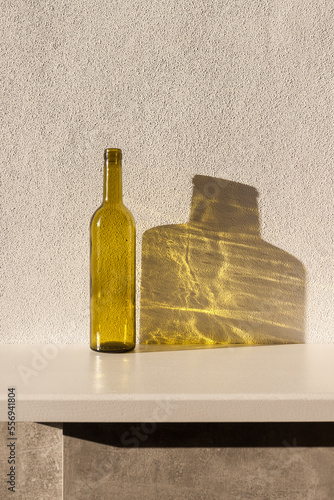 A bottle of wine in sunlight and its colored shadow. long shadow and refraction patterns. White background