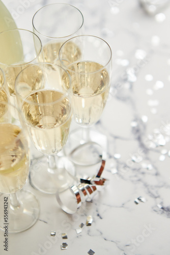 Champagne glasses and bottle placed on white marble background