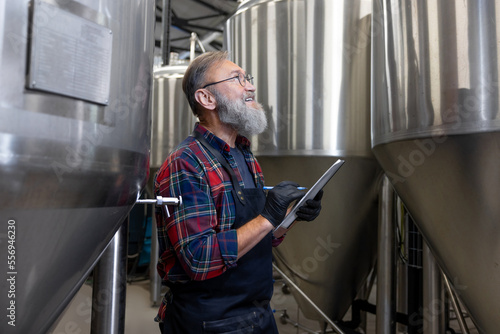 Man in plaid shirt checnking the tanks with beer at the brewery