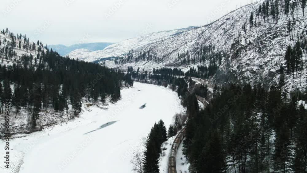 Experience the Beauty of Winter in British Columbia: Aerial Shot Follows Freight Train Along the Frozen North Thompson River and Yellowhead Highway 5 Near Kamloops Experience the Beauty of Winter in British Columbia: Aerial Shot Follows Freight Train Along the Frozen North Thompson River and Yellowhead Highway 5 Near Kamloops