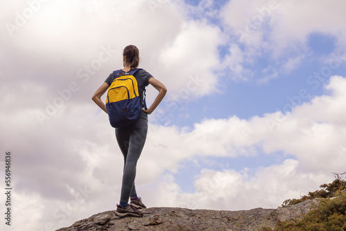 Young woman with backpack rise to the mountain top. Discovery Travel