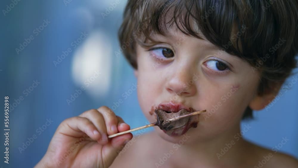 Closeup child face finishing icecream dessert. Messy young boy mouth covered in chocolate enjoying ice cream Closeup child face finishing icecream dessert. Messy young boy mouth covered in chocolate enjoying ice cream
