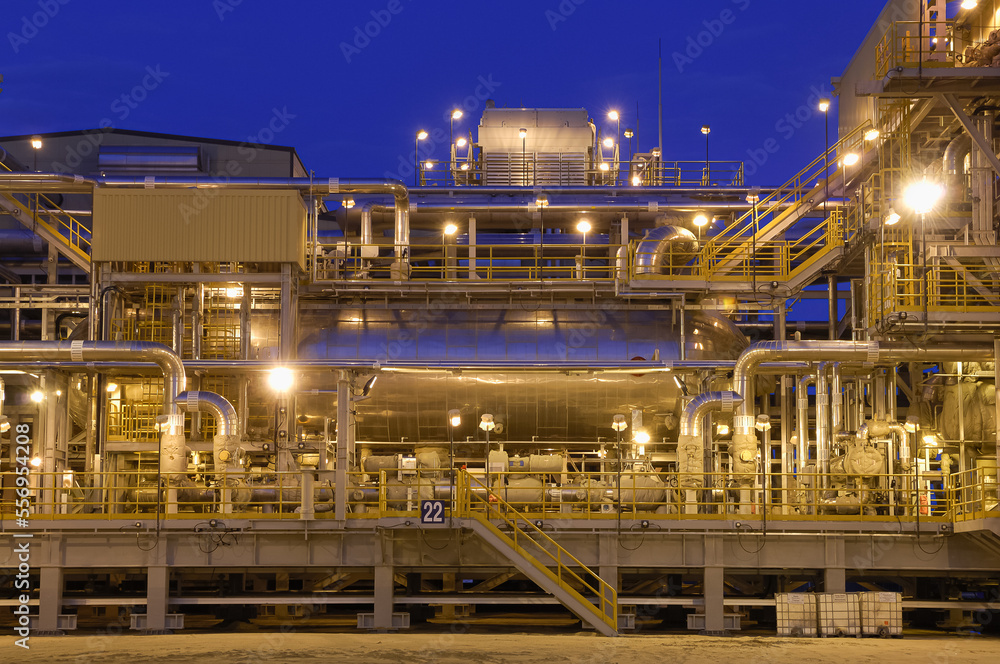 Night view of the equipment of a gas field with a large number of pipes.