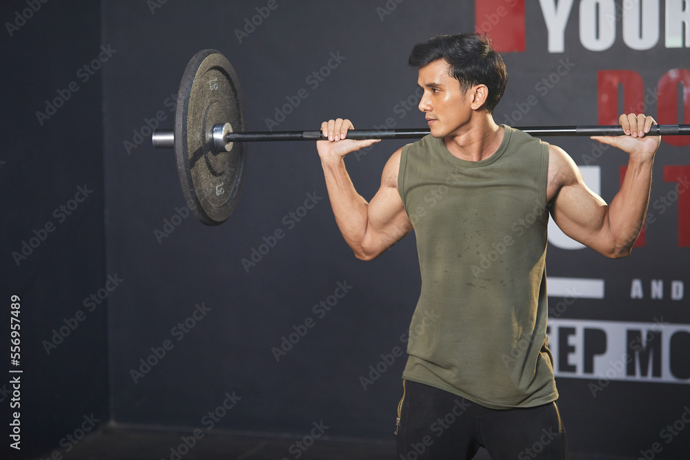 young athletic man exercising with barbell in the gym young athletic man exercising with barbell in the gym