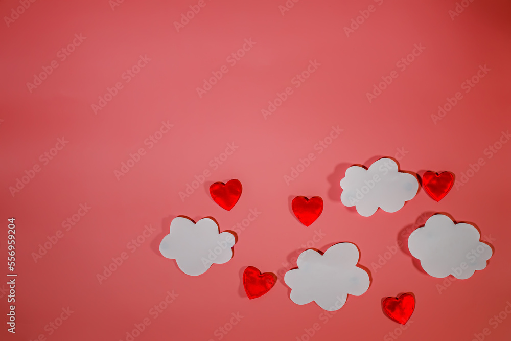 White paper clouds and red textile hearts on a red background. Conceptual background for Valentine's Day or Women's Day. Copy space