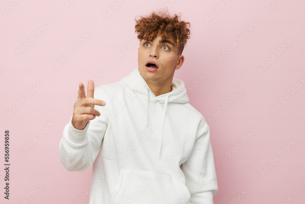a funny, shocked man stands on a pink background in a white hoodie and looks at the toron with his mouth wide open in surprise and points his fingers towards the empty space in the background a funny, shocked man stands on a pink background in a white hoodie and looks at the toron with his mouth wide open in surprise and points his fingers towards the empty space in the background