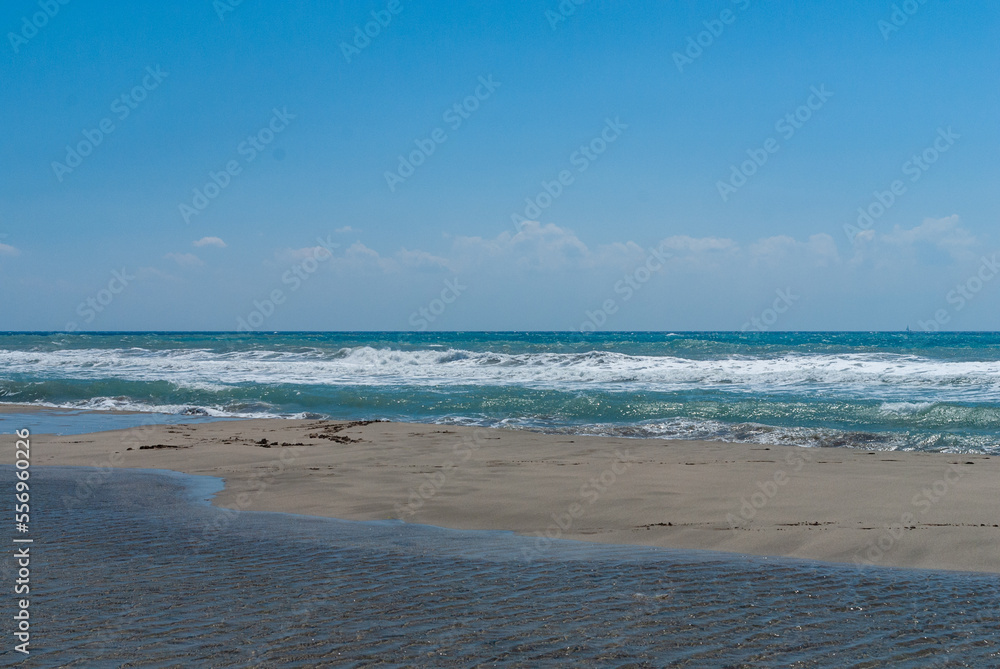 Fethiye, Turkey. Coast of Mediterranean Sea. Turquoise foamy waves. Sand beach. Close-up. Sunny autumn day.