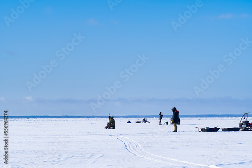 Ice Fishing. Winter fishing on ice at sea, Estonia. Anglers with equipment fishing on the lake ice