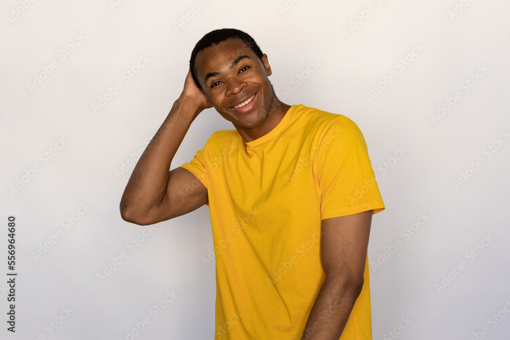 Portrait of happy young man touching head and looking at camera over white background. African American guy wearing yellow T-shirt standing and laughing. Happiness concept Portrait of happy young man touching head and looking at camera over white background. African American guy wearing yellow T-shirt standing and laughing. Happiness concept