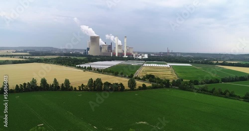 4K aerial drone footage of a large coal fired power station with cooling towers, chimney and boiler house in an air pollution or carbon footprint concept