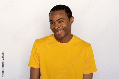 Portrait of cheerful young man looking at camera and smiling. African American guy wearing yellow T-shirt posing against white background. Happiness concept