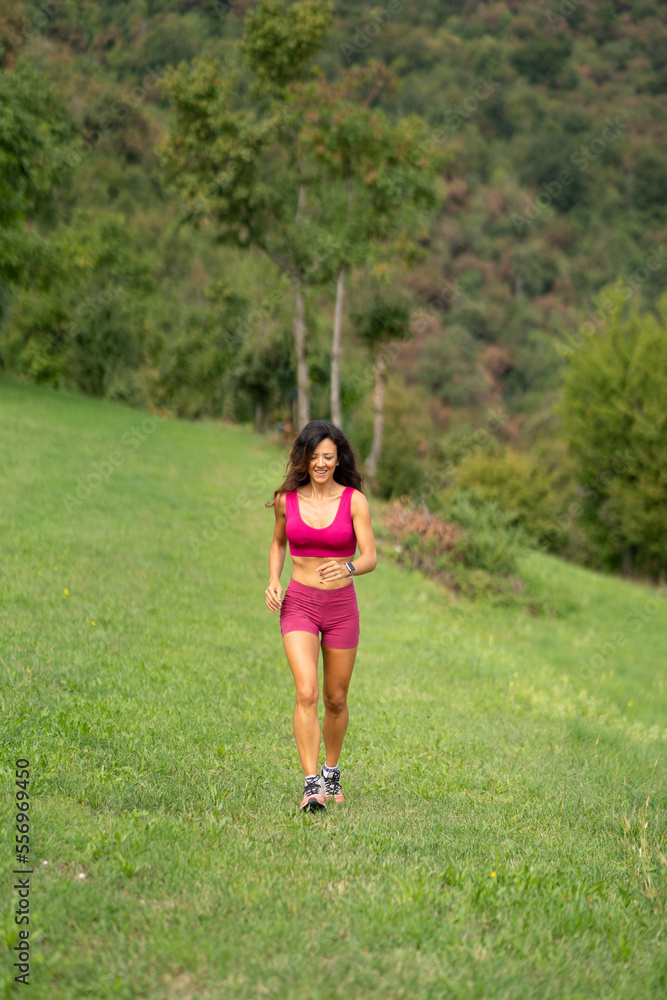 Trail running smiling girl runs uphill and on trail 