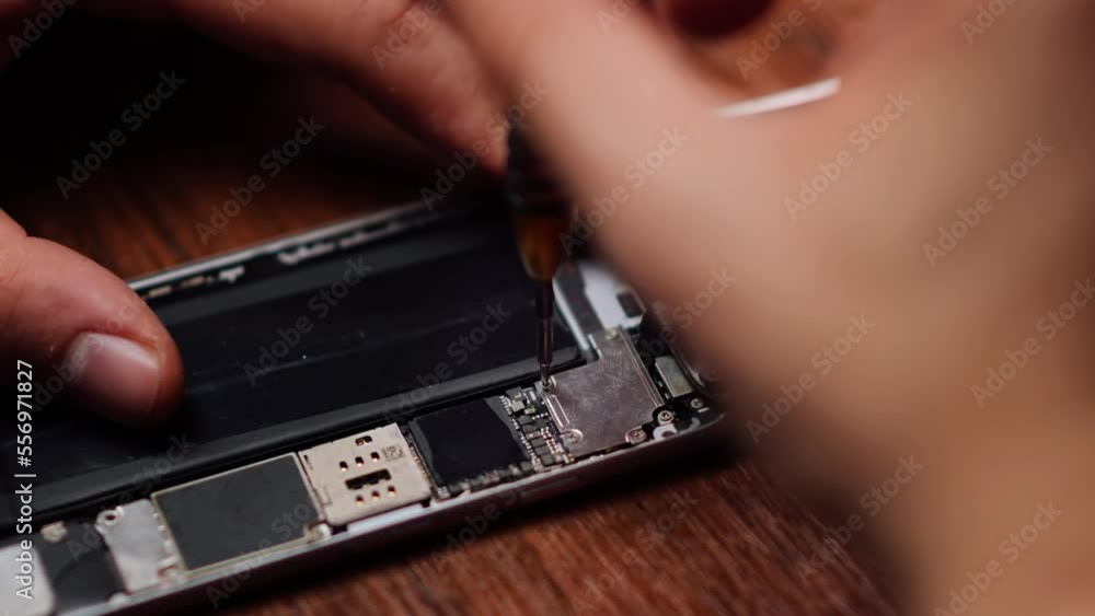 Locked down and close up of technician or engineer repairing or replace new parts of broken and damaged smartphone on desk Locked down and close up of technician or engineer repairing or replace new parts of broken and damaged smartphone on desk
