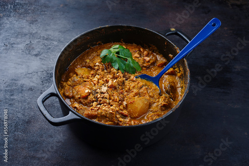Traditional Indian vegetarian Madras curry stew with sweet potatoes and roasted cashew nuts served as close-up in saucepan