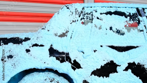 Classic car being washed with blue foam.