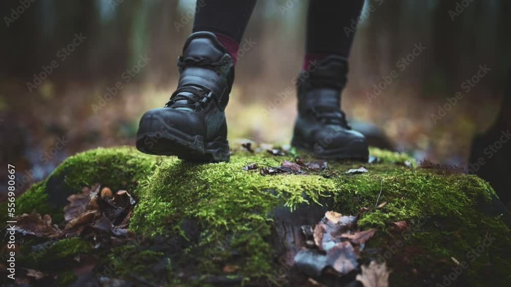 Close-up of person feet in shoes walking along damp, wet, dirty ground on path in forest. Travel and hiking. Enjoying wild alone on journey. Healthy active lifestyle in sport. Unrecognizable person. Close-up of person feet in shoes walking along damp, wet, dirty ground on path in forest. Travel and hiking. Enjoying wild alone on journey. Healthy active lifestyle in sport. Unrecognizable person.