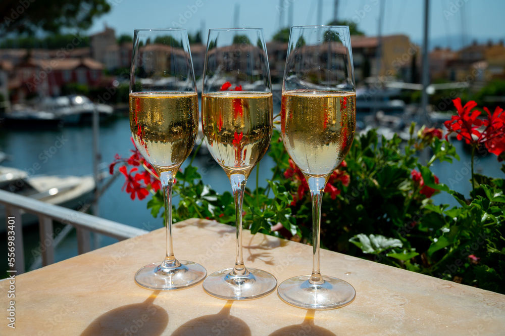 Drinking of French brut champagne sparkling wine in glasses in yacht harbour of Port Grimaud near Saint-Tropez, French Riviera vacation, France Drinking of French brut champagne sparkling wine in glasses in yacht harbour of Port Grimaud near Saint-Tropez, French Riviera vacation, France