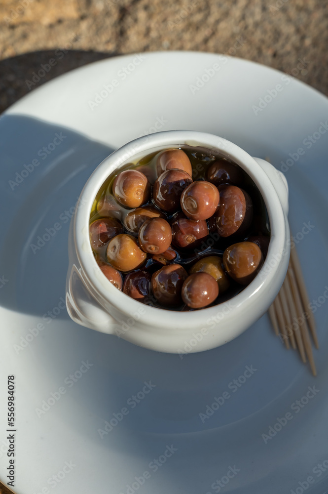 Small pickled brown olives as pairing for red dry beaujolais wine served outdoor in France, Beaujolais region.