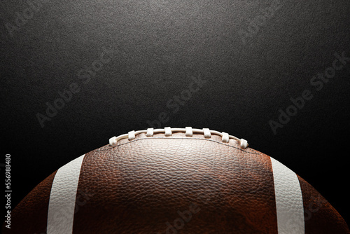 American football ball on dark textured background with space for text.