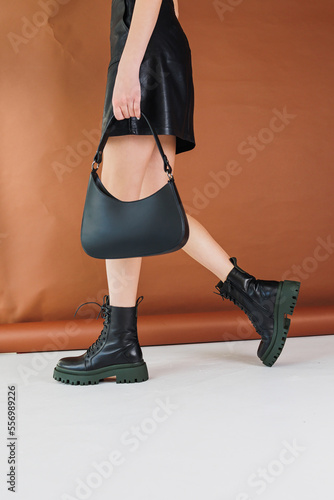 Close-up of female legs in black leather boots. Women's winter shoes. Warm women's boots. Women's modern shoes