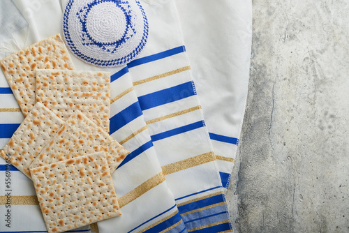 Passover celebration concept. Matzah, red kosher and walnut. Traditional ritual Jewish bread matzah, kippah and tallit on old concrete background. Passover food. Pesach Jewish holiday.