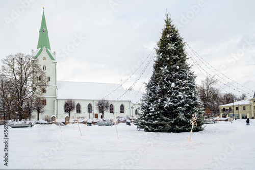 A decorated Christmas tree in a town square with a church in the background, Dobele, Latvia