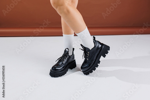 Beautiful female legs in leather black lace-up oxford shoes. Female legs with fashionable shoes and white socks. Casual black women's shoes photo