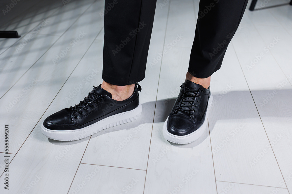 Modern men's shoes. Male legs in black pants and black casual sneakers. Men's fashionable shoes Modern men's shoes. Male legs in black pants and black casual sneakers. Men's fashionable shoes