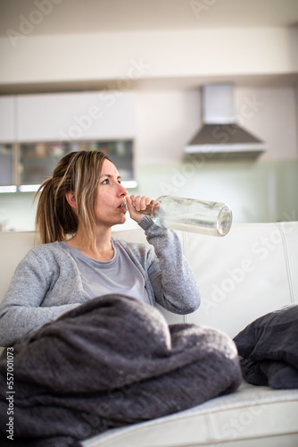 Midlle aged woman at home with a bottle of strong alcohol in her hands