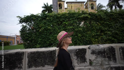Happy mature woman wearing a hat, walking by Santa Ana church in Merida, Yucatan, Mexico. photo