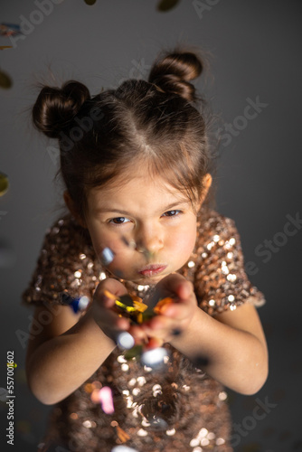 Lovely girl blowing multi colored confetti. Party photo concept.