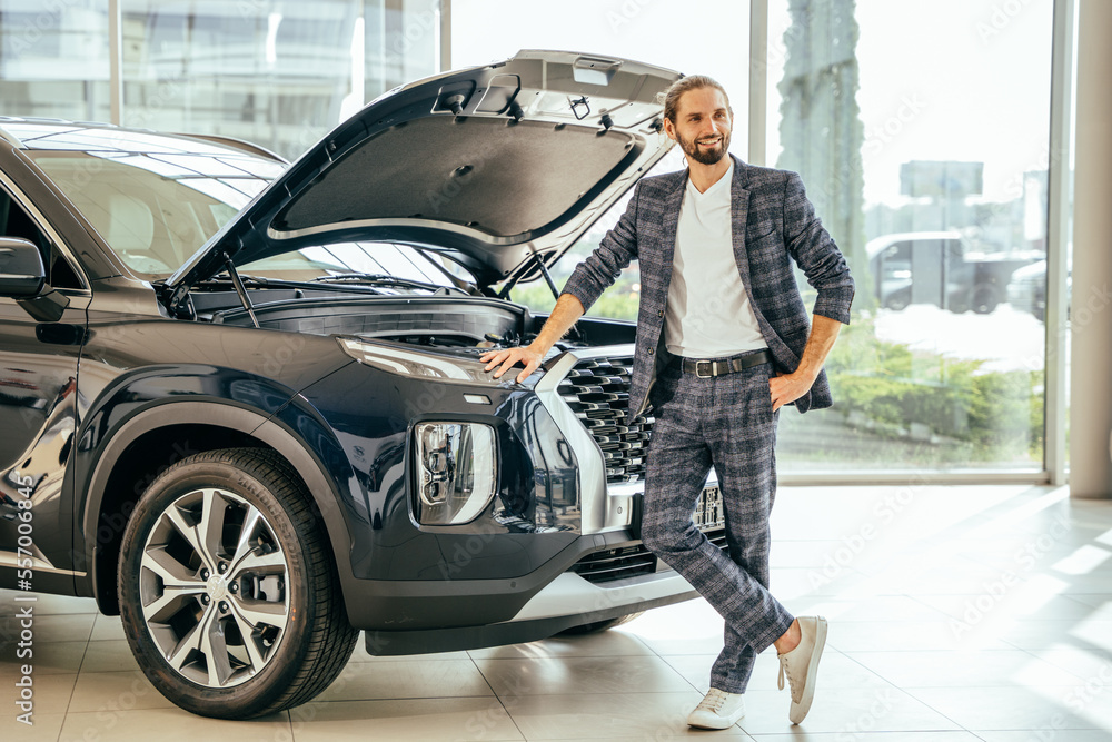 Successful businessman choosing a car at the dealership examining engine of an auto male customer looking at the engine of a new car at the dealership success buy purchase choice.