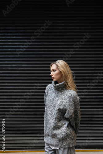 trendy young woman in winter outfit standing and looking away outdoors