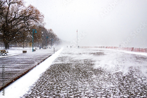 Photography People embrace winter as snow and wind blow across a bleak frozen beach